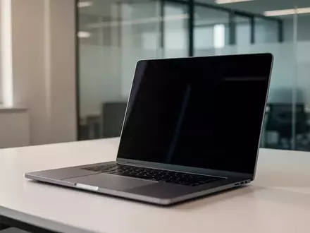 Ein minimalistischer Arbeitsplatz mit einem Laptop, dessen Bildschirm dunkel und unbeschriftet ist, in einem modernen Büro. - Foto: über boerse-global.de