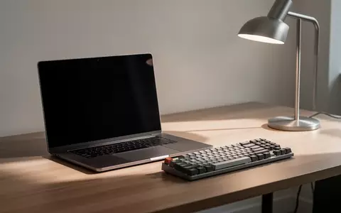 Ein minimalistischer Arbeitsplatz mit einem Laptop mit dunklem Bildschirm und einer mechanischen Tastatur auf einem Holztisch. - Foto: über boerse-global.de