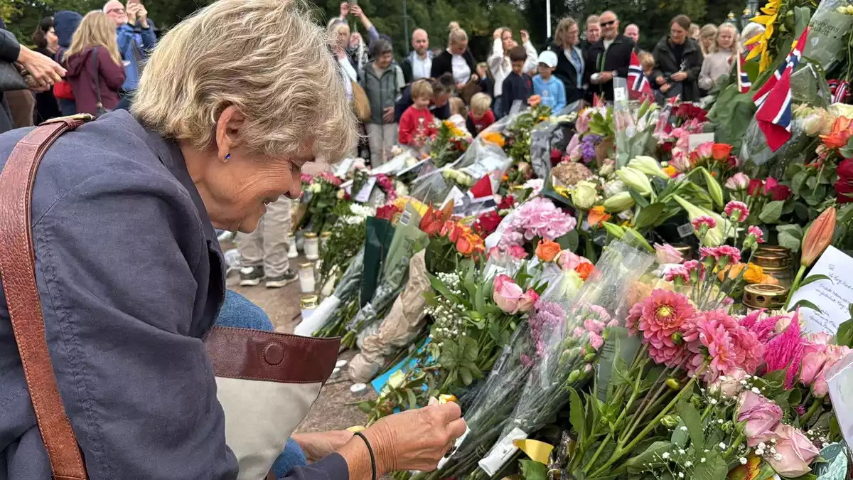 Anne Sandø Seierstad zündet eine Kerze für den gestorbenen Monarchen an.  - Bild: Julia Wäschenbach/dpa