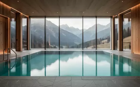 Ein leeres, modernes Hallenbad in einem alpinen Resort mit Blick auf die Berge, helles und klares Wasser. - Foto: über boerse-global.de