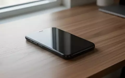 Ein modernes Smartphone liegt mit ausgeschaltetem Bildschirm auf einem schlichten Schreibtisch aus Holz. - Foto: über boerse-global.de