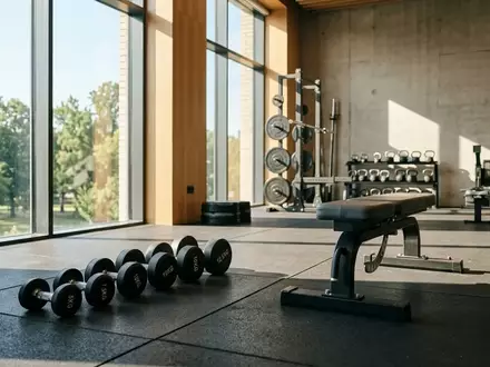 Hanteln und Fitnessgeräte in einem hellen, aufgeräumten Fitnessraum bei natürlichem Lichteinfall. - Foto: über boerse-global.de