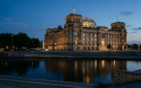Das Reichstagsgebäude in Berlin bei Dämmerung mit beleuchteten Fenstern vor einem tiefblauen Abendhimmel. - Foto: über boerse-global.de