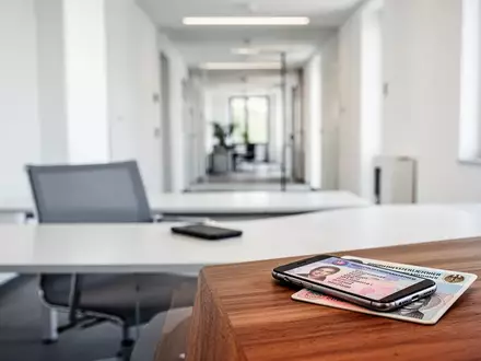 Ein Smartphone und ein Personalausweis auf einem Schreibtisch in einem modernen Büro der Bundesagentur für Arbeit. - Foto: über boerse-global.de