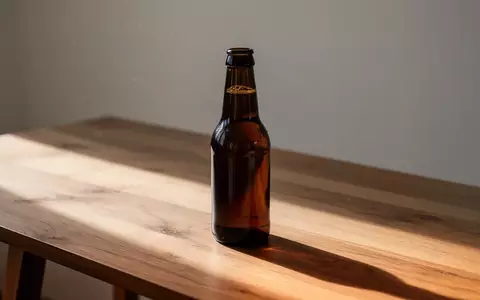 Eine einzelne Bierflasche auf einem Holztisch bei natürlichem Lichteinfall. - Foto: über boerse-global.de