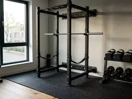 Ein professionelles Power Rack und verstellbare Hanteln in einem modernen, minimalistischen Fitnessraum. - Foto: über boerse-global.de