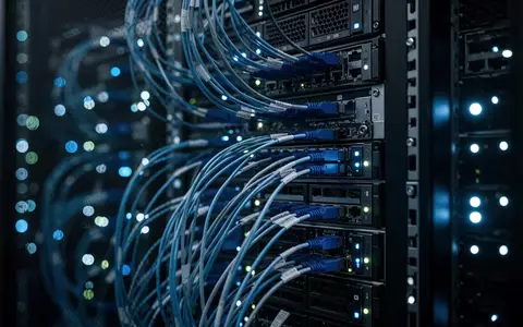 Dunkler Serverraum mit leuchtenden LED-Anzeigen an Server-Racks und komplexer Verkabelung in einem modernen Rechenzentrum. - Foto: über boerse-global.de