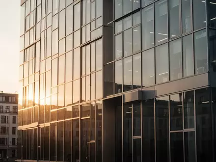 Moderne Glasfassade eines Bürogebäudes in Berlin bei Sonnenuntergang als Symbol für den Standort des KI-Sicherheitsinstituts. - Foto: über boerse-global.de