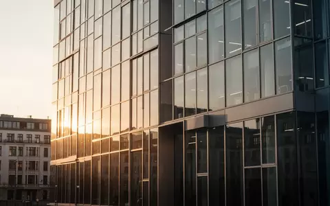 Moderne Glasfassade eines Bürogebäudes in Berlin bei Sonnenuntergang als Symbol für den Standort des KI-Sicherheitsinstituts. - Foto: über boerse-global.de
