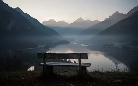 Eine minimalistische, ruhige Berglandschaft in der Abenddämmerung mit einer einsamen Holzbank mit Blick auf ein nebliges Tal. - Foto: über boerse-global.de