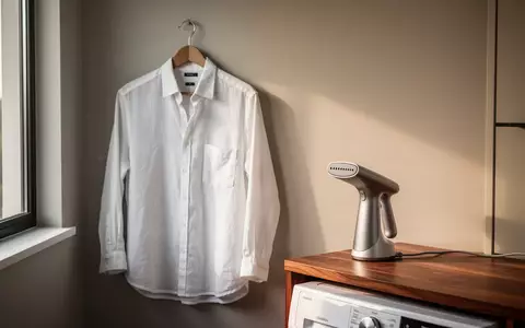 Ein hängendes weißes Leinenhemd und ein kompakter Dampfglätter in einem minimalistisch eingerichteten, hellen Raum. - Foto: über boerse-global.de