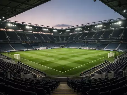 Leeres, beleuchtetes Fußballstadion in der Abenddämmerung mit Blick auf den Rasen. - Foto: über boerse-global.de