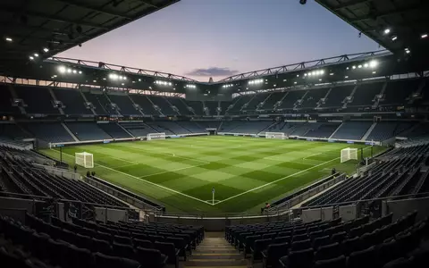 Leeres, beleuchtetes Fußballstadion in der Abenddämmerung mit Blick auf den Rasen. - Foto: über boerse-global.de