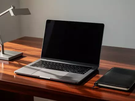 Ein minimalistischer Arbeitsplatz mit einem Laptop mit dunklem Bildschirm und einem Notizbuch auf einem Schreibtisch. - Foto: über boerse-global.de