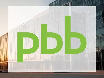 Moderne Glasfassade eines Verwaltungsgebäudes bei goldenem Licht, symbolisch für Immobilienfinanzierung und Stabilität. - Foto: über boerse-global.de