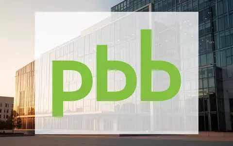 Moderne Glasfassade eines Verwaltungsgebäudes bei goldenem Licht, symbolisch für Immobilienfinanzierung und Stabilität. - Foto: über boerse-global.de