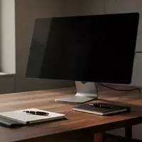 Ein aufgeräumter, moderner Büroarbeitsplatz mit einem ausgeschalteten Computermonitor und einem Notizbuch auf einem Holztisch. - Foto: über boerse-global.de