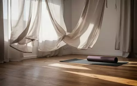 Ein minimalistischer, lichtdurchfluteter Trainingsraum mit einer zusammengerollten Yogamatte auf einem Holzboden. - Foto: über boerse-global.de