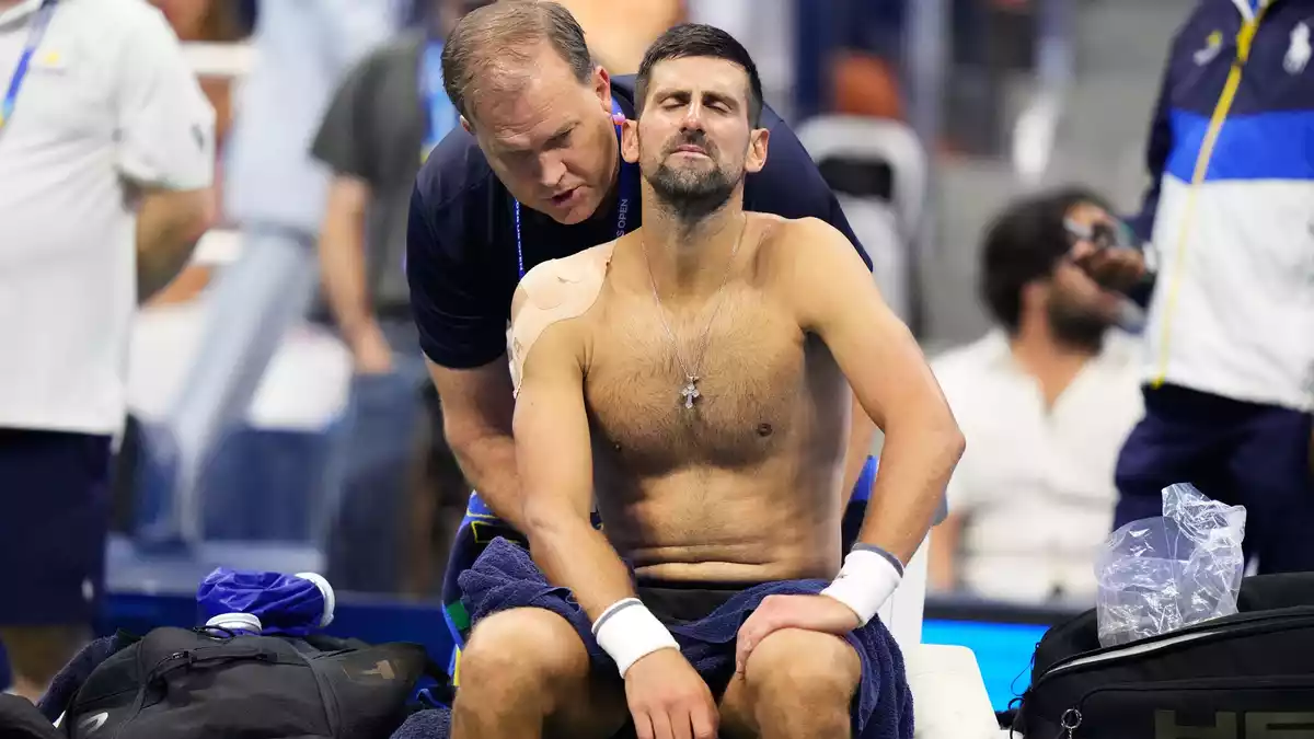 Im fünften Satz wird Novak Djokovic am Rücken behandelt. - Bild: Frank Franklin II/AP/dpa