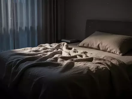 Ein ungemachtes Bett in einem sanft beleuchteten, ruhigen Schlafzimmer bei Dämmerlicht. - Foto: über boerse-global.de