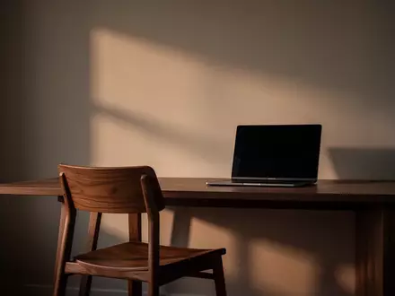 Ein leerer Schreibtisch mit einem ausgeschalteten Laptop in einer ruhigen, schattigen Büroumgebung. - Foto: über boerse-global.de