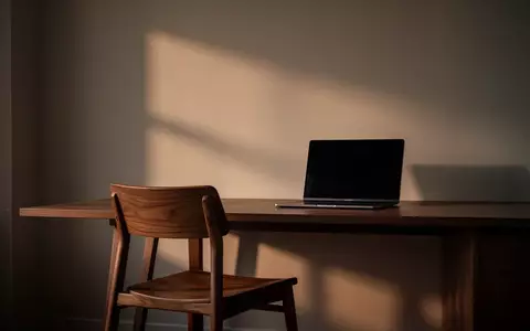Ein leerer Schreibtisch mit einem ausgeschalteten Laptop in einer ruhigen, schattigen Büroumgebung. - Foto: über boerse-global.de