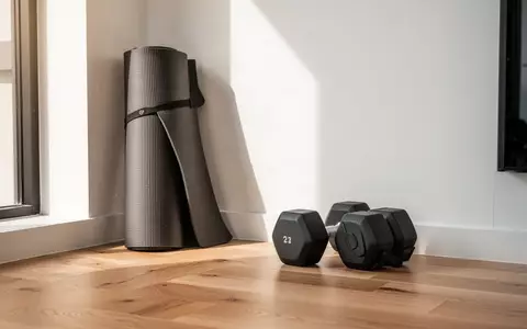 Minimalistisches Home-Gym mit einer zusammengerollten Yogamatte und zwei Hanteln auf einem hellen Holzboden. - Foto: über boerse-global.de