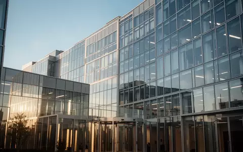 Modernes Bürogebäude aus Glas vor einem klaren blauen Himmel. - Foto: über boerse-global.de