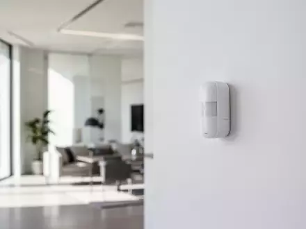 Modernes, minimalistisches Wohninterieur mit einem unauffälligen Sicherheitssensor an einer weißen Wand. - Foto: über boerse-global.de