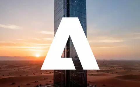 Moderne Glasfassade eines Wolkenkratzers vor einer Wüstenlandschaft bei Sonnenaufgang als Symbol für technologische Expansion. - Foto: über boerse-global.de