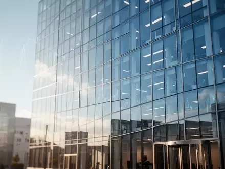 Moderne Glasfassade eines Bürogebäudes vor blauem Himmel. - Foto: über boerse-global.de