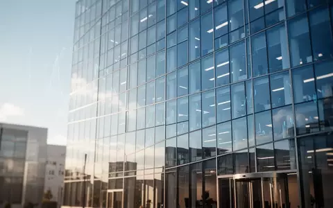 Moderne Glasfassade eines Bürogebäudes vor blauem Himmel. - Foto: über boerse-global.de