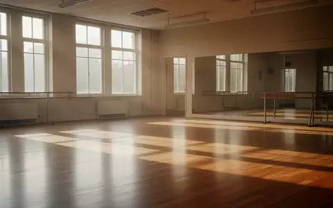 Ein leerer, sonnendurchfluteter Tanzsaal mit Parkettboden und großen Fenstern, der eine Atmosphäre von Gemeinschaft und Bewegung vermittelt. - Foto: über boerse-global.de