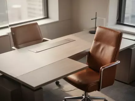 Ein minimalistischer Büroschreibtisch mit einem leeren Stuhl in natürlichem Licht. - Foto: über boerse-global.de