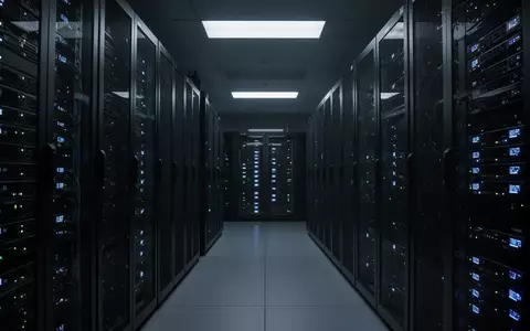 Dunkler Serverraum mit leuchtenden blauen Status-LEDs an den Gehäusen, die eine sterile und technisch-kühle Atmosphäre erzeugen. - Foto: über boerse-global.de