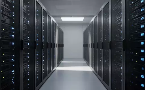 Moderne Serverräume mit leuchtenden LED-Statusanzeigen in einer technologisch geprägten Büroumgebung. - Foto: über boerse-global.de