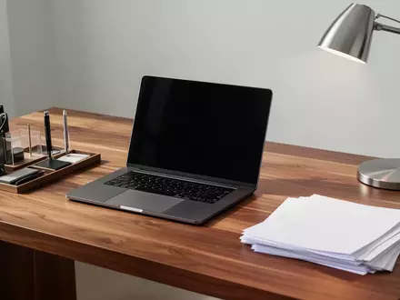 Ein aufgeräumter Schreibtisch mit einem ausgeschalteten Laptop, Schreibwaren und leeren Dokumenten in natürlichem Licht. - Foto: über boerse-global.de