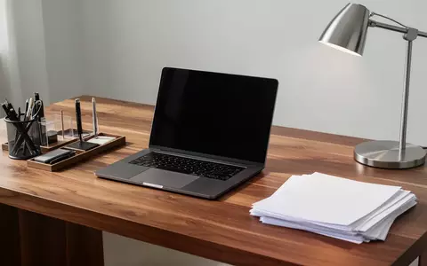 Ein aufgeräumter Schreibtisch mit einem ausgeschalteten Laptop, Schreibwaren und leeren Dokumenten in natürlichem Licht. - Foto: über boerse-global.de