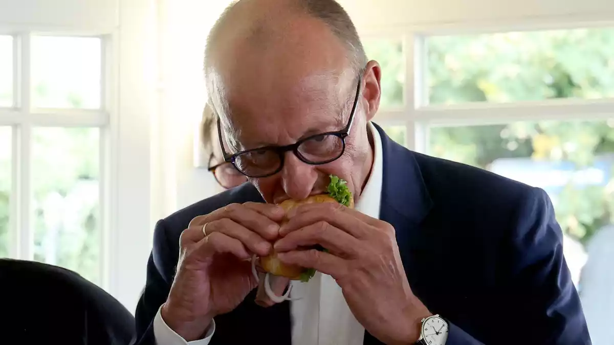 Das Fischbrötchen ließ sich der Kanzler schmecken. - Bild: Bernd Wüstneck/dpa