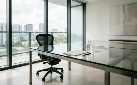 Ein minimalistisches, modernes Büro mit einem leeren Schreibtisch und einem ergonomischen Stuhl in hellem Tageslicht. - Foto: über boerse-global.de