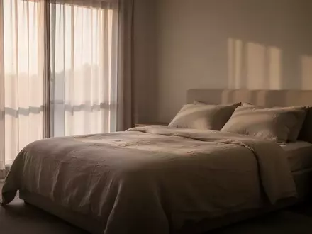 Ein minimalistisch eingerichtetes, ruhiges Schlafzimmer bei sanftem Morgenlicht, das eine Atmosphäre der Erholung vermittelt. - Foto: über boerse-global.de