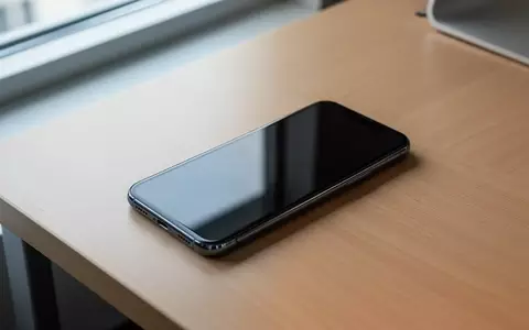 Ein modernes Smartphone liegt mit ausgeschaltetem, dunklem Display auf einem minimalistischen Schreibtisch. - Foto: über boerse-global.de