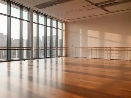 Ein heller, leerer Tanzsaal mit Parkettboden und großen Fenstern, durch die natürliches Tageslicht fällt. - Foto: über boerse-global.de