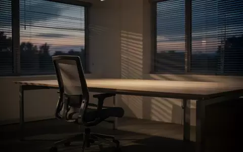 Ein leerer, minimalistischer Arbeitsplatz in einem Büro bei Dämmerung, der eine ruhige und nachdenkliche Atmosphäre ausstrahlt. - Foto: über boerse-global.de