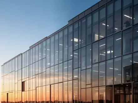 Moderne Glasfassade eines Bürogebäudes bei Sonnenuntergang als Symbol für Konzernstrukturen. - Foto: über boerse-global.de