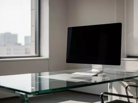 Ein moderner, minimalistischer Büroarbeitsplatz mit einem ausgeschalteten Monitor vor einem großen Fenster. - Foto: über boerse-global.de