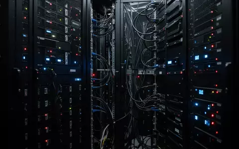 Dunkler Serverraum mit beleuchteten Server-Racks, die die digitale Sicherheitsinfrastruktur symbolisieren. - Foto: über boerse-global.de