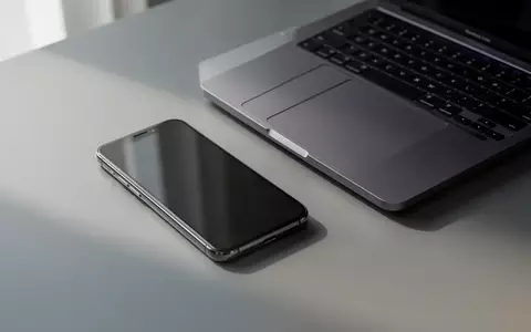 Ein modernes Smartphone liegt neben einem Laptop auf einem Schreibtisch in einer hellen, minimalistischen Büroumgebung. - Foto: über boerse-global.de