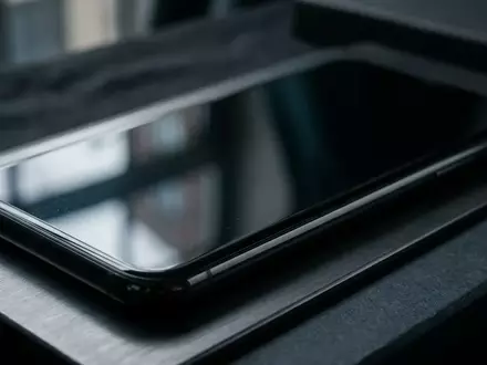 Nahaufnahme einer modernen Smartphone-Displayoberfläche in einer minimalistischen, dunklen Umgebung ohne sichtbare Inhalte. - Foto: über boerse-global.de