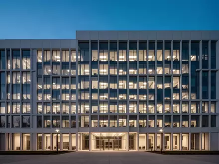 Modernes Verwaltungsgebäude in der Dämmerung mit beleuchteten Fenstern. - Foto: über boerse-global.de